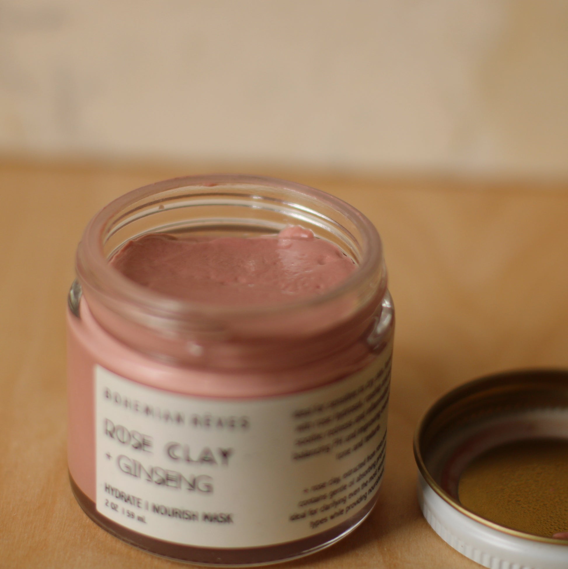 open jar with pink balm inside with marble background